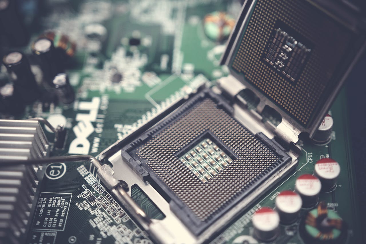 gallery-05 Detailed close-up shot of a computer motherboard featuring an open CPU socket and electronic components.