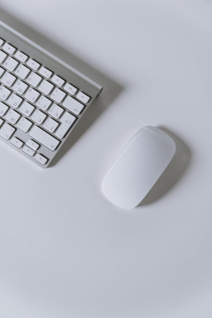 services-img A clean and modern minimalist workspace featuring a white keyboard and mouse on a white surface.